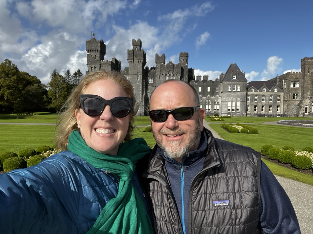 Susan Green and her husband at Ashford Castle in County Mayo, Ireland, with the castle and gardens behind