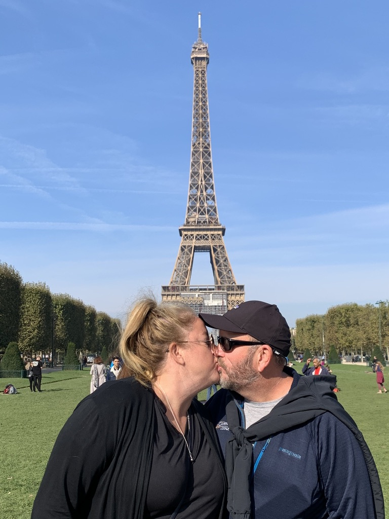 Susan Green and her husband sharing a kiss on the Champ de Mars below the Eiffel Tower in Paris, France