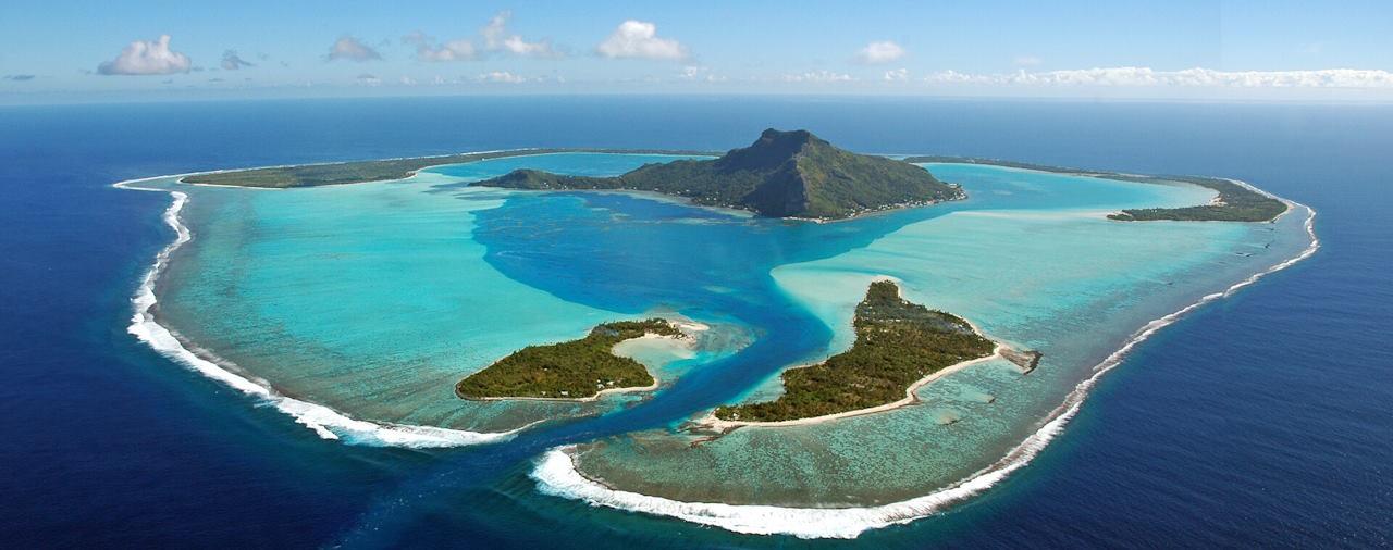 Aerial view of Maupiti, French Polynesia, with its mountainous island, turquoise lagoon, motus and surrounding reef