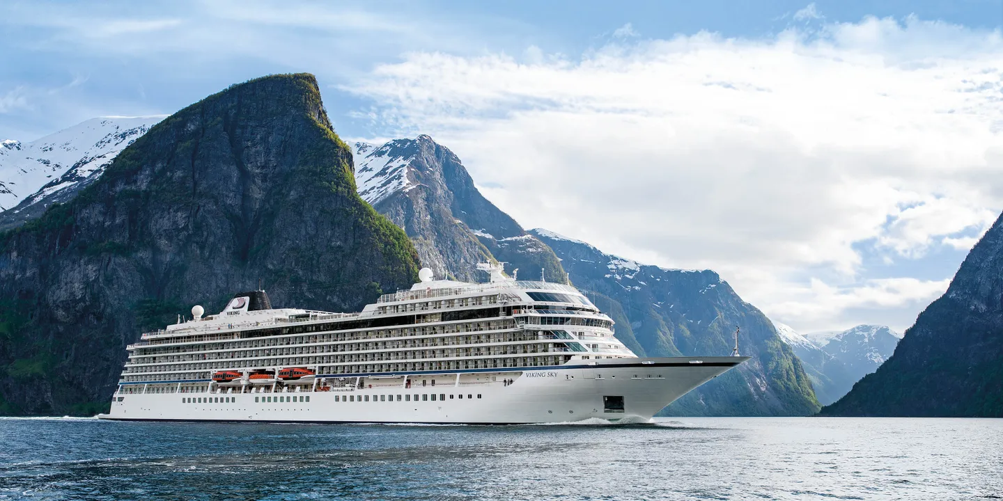 Viking Sky cruise ship sailing a fjord beneath snow-capped mountains
