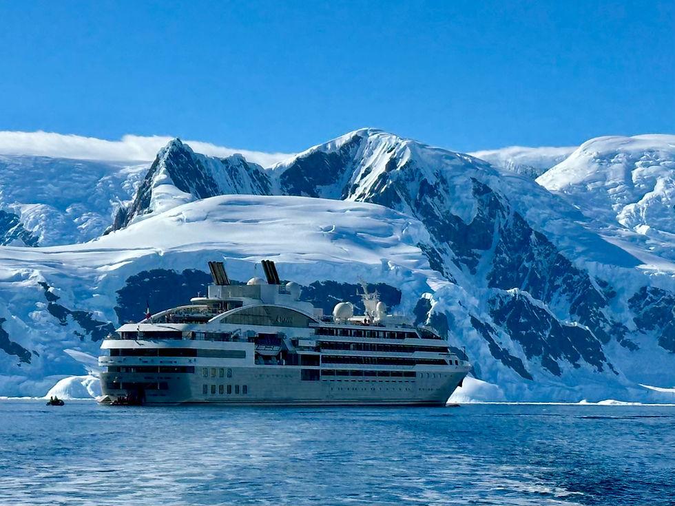 Abercrombie & Kent expedition cruise aboard a Ponant ship below snowy mountains in Antarctica