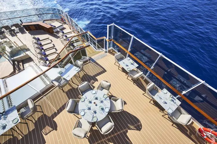 Open-air teak dining terrace set for lunch above the sea