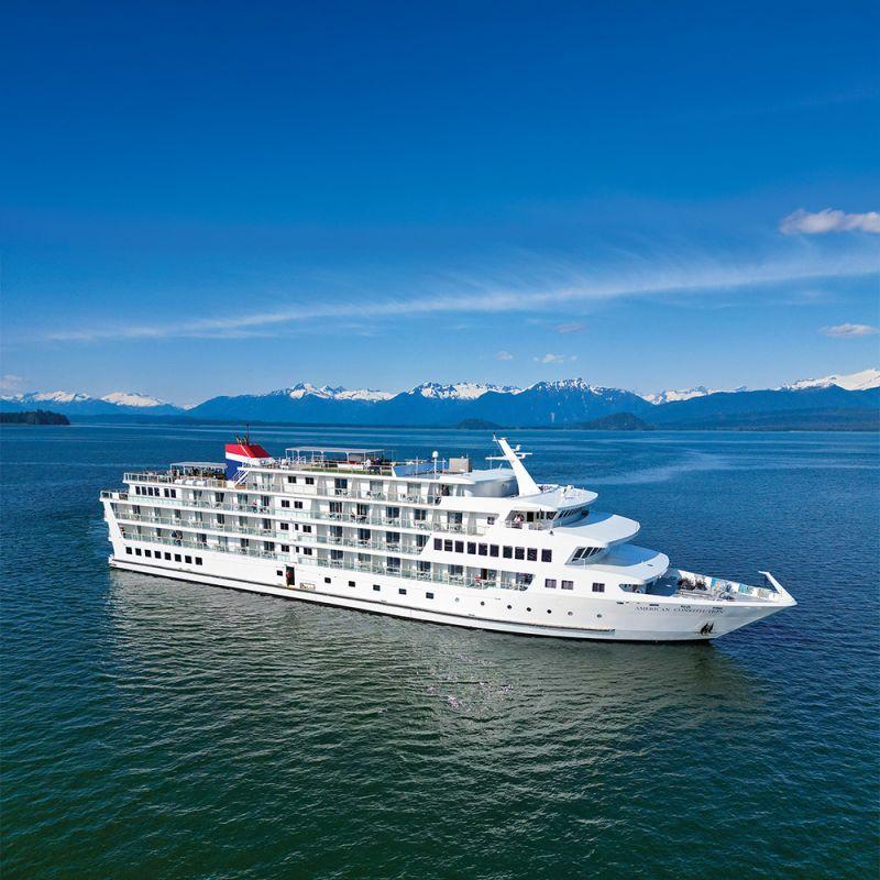 American Cruise Lines' American Constitution cruising Alaska's Inside Passage below snow-capped mountains