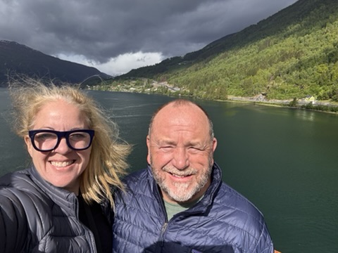 Susan Green and her husband on their Seabourn cruise balcony above a green fjord in Norway