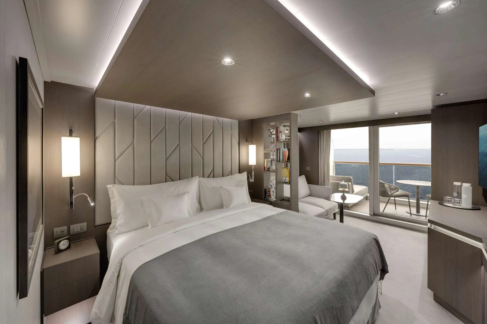 Ocean Terrace Suite bedroom with sitting area and private terrace overlooking the sea