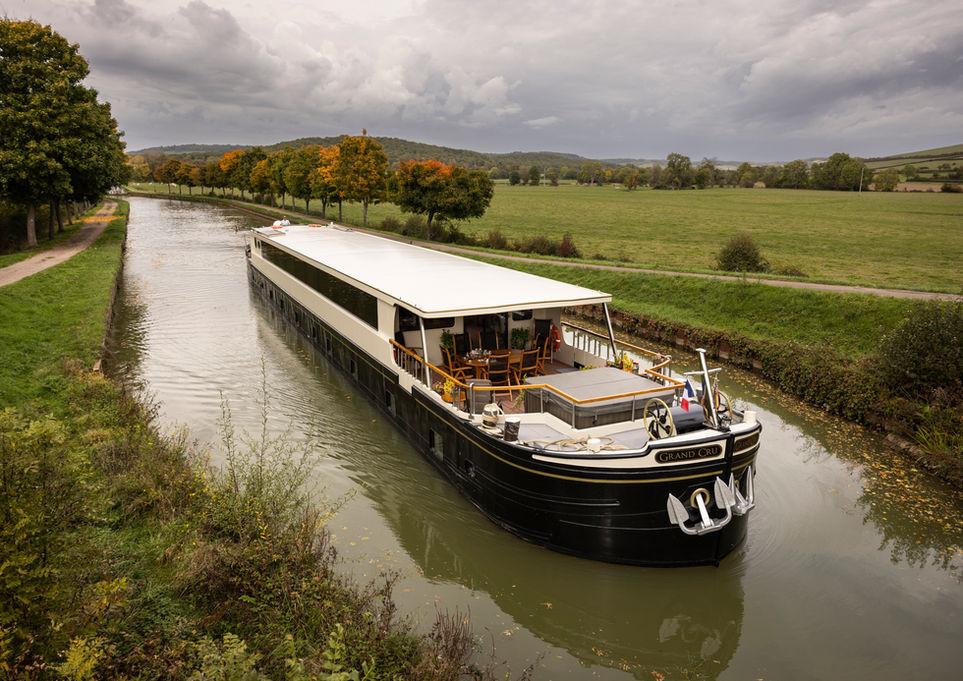 Hotel barge on a tree-lined canal in Burgundy, France, in autumn