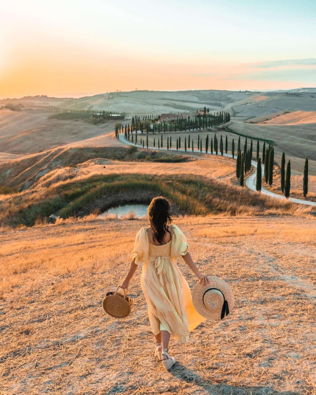 A winding cypress-lined road through the golden hills of Val d'Orcia in Tuscany, Italy