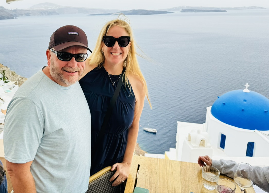 Susan Green and her husband overlooking the blue-domed churches and caldera of Oia, Santorini, Greece